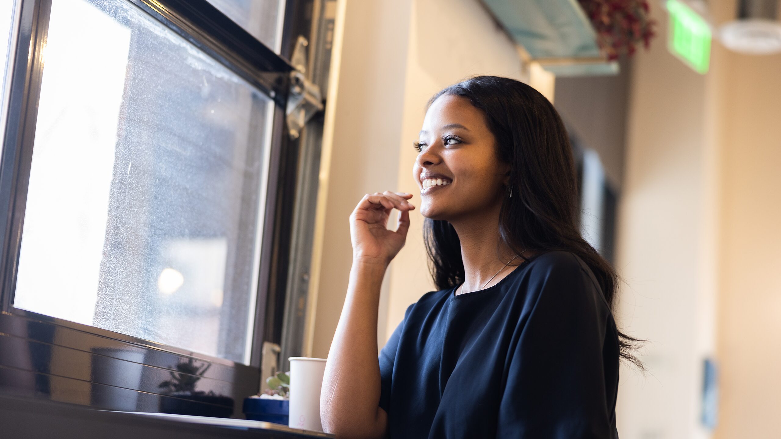 Woman looking out the window of a cafe.